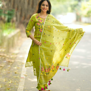 Woman in a green traditional outfit with a floral dupatta standing outdoors.