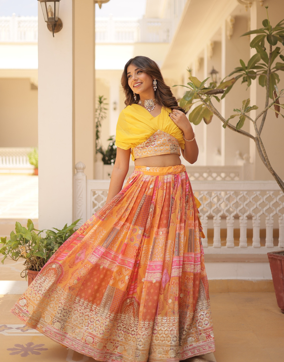 Woman in a yellow top and patterned skirt standing in a decorative outdoor setting.